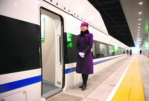A stewardess waits to greet journalists boarding a high-speed train at the Beijing West Railway Station. China showed off the final link of the world's longest high-speed rail line, set to open on Dec 26. Trains will travel the 2,298 km (1,425 mile) route from Beijing to Canton at over 300 kph.