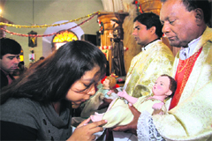 A girl kisses the feet of Baby Christ at a prayer meeting at St Francis Church on Christmas in Dehradun on Tuesday. 