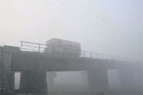 A truck moves on a bridge amid heavy fog in Jammu on Tuesday