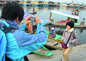 A tourist takes a photograph on the banks of the Dal Lake in Srinagar on Tuesday