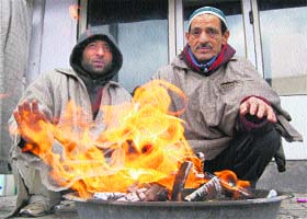 Shopkeepers sit beside a bonfire at Lal Chowk in Srinagar on Tuesday