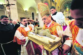 Foud Twal, the Latin Patriarch of the Holy Land, holds a replica of the baby Jesus in Saint Catherine's Church at the end of the Christmas Midnight Mass, early on Tuesday in Bethlehem