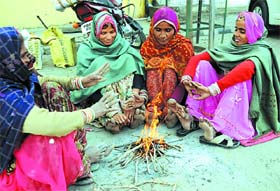 Winter warmth: Women light a fire to keep themselves warm as the chill intensified in the city