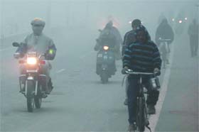 Commuters make their way through a blanket of fog that enveloped the city in the morning