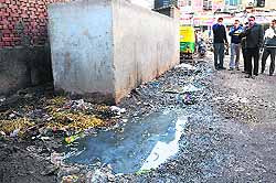 Shopkeepers cover their noses due to the foul smell emanating from a choked sewerage at the Grain Market