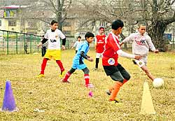 Children play football at Polo Ground in Srinagar on Wednesday