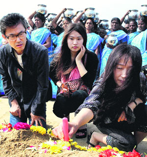 Foreign tourists offer prayers for the victims of the 2004 tsunami at Marina Beach in Chennai on Wednesday.