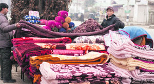A vendor sells blankets on a footpath in Srinagar on Thursday