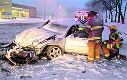 Rescuers work to move a driver injured in a wreck on snow-covered street in Columbus, US, on Wednesday