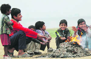 Children gather around fire in Jammu on Friday. 