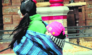 A woman carries her child wrapped in woolen clothes in Jammu on Friday.  