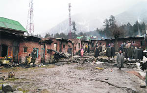 Houses damaged in a fire in Sheikh Colony of Pahalgam on Friday. 