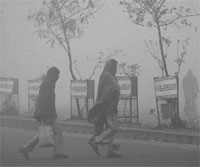 People brave the chill on a foggy Friday morning in Lucknow. PTI