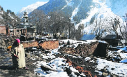A woman walks through the debris of the houses gutted in a fire at Frislan village in Anantnag. tribune photo: Amin War 