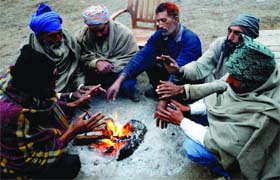 People sit by a bonfire to beat the chill in Amritsar on Sunday