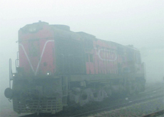An engine makes its way through the dense fog on the railway track near Santpura road on Sunday. Fog has hit rail traffic in the area. 