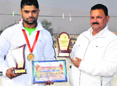 Harshwardhan Sharma, who won the silver medal in the North India National Body Building Championship held in Rajasthan recently, with his father in Haridwar on Saturday. 