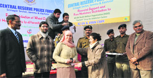 A CRPF official distributes hearing aid to differently-abled persons in Srinagar on Sunday.