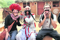 A performing artiste along with tourists during the Shilpgram festival at a village near Udaipur on Sunday.