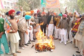 Members of the Bharatiya Kisan Morcha burn an effigy of the Central Government