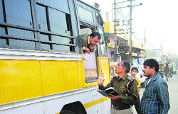 A cop stops a bus for using black films in Rohtak on Wednesday. 
