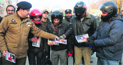 A Traffic Police official distributes New Year gift cards to two-wheeler drivers found abiding by traffic norms in Srinagar on Tuesday. Photo: Amin War