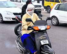 A scooterist is wrapped in woolens as she rides through the cold wave conditions in Jammu on Wednesday