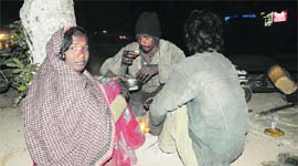 Homeless have food alongside the main road in Sector 22 on Wednesday night.