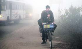 A man pedals his way through the fog to drop his children to school in Jammu.