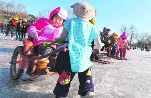 A Chinese girl rides a battery-powered cart pulled by a puppet at the frozen Houhai Lake in Beijing on Thursday. The lake attracts scores of tourists and locals despite winter temperatures as low as minus 18C.