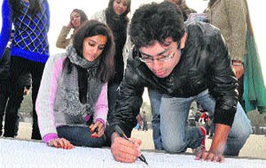 A student writes his message during the ABVP signature campaign at Sector 17 in Chandigarh on Friday.
