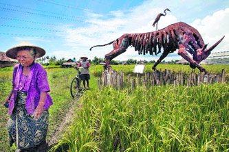 Farmers walk by a sculpture entitled “Bull get injured” by artist Budi Barnabas at Nitiprayan village in Bantul, near Yogyakarta, Indonesia. The work was part of an outdoor sculpture exhibition called “Last Harvest” that included works from 30 artists voicing concerns over diminishing agricultural land.