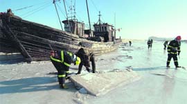 Investigators inspect a port where ships are stranded in ice, in Jinzhou, Liaoning province, on Saturday.