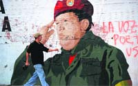 A man walks past a painting of Venezuelan President Hugo Chavez in Caracas.