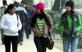 Girls cover themselves with woollies to fight the cold wave in New Delhi on Sunday.
