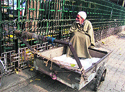 An elderly man sits on a hand cart in Srinagar on Sunday