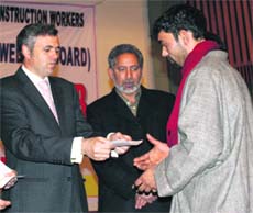 Chief Minister Omar Abdullah gives a cheque to a registered construction worker during a function in Srinagar on Sunday. 