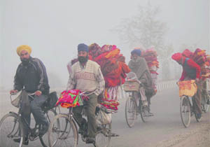 Braving the cold weather and fog,  roadside blanket sellers ferry their goods towards Jammu, on the outskirts of the city. 