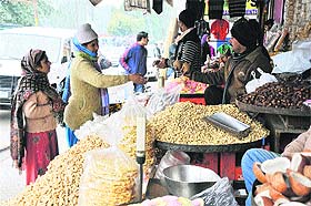 A shopkeeper sells groundnuts and other food items at a market in Jammu on Monday.