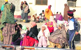 Passengers waiting for various trains sit on the platform under the open sky during bone-chilling cold weather as no extra arrangements have been made for them to keep them warm.