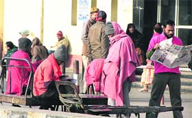 Porters sit idle as majority of the trains run several hours late at the city railway station in Jalandhar.