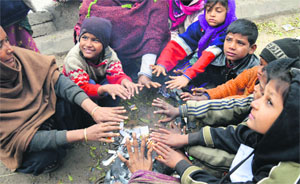 People sit alongside a bonfire to keep themselves warm in Ludhiana on Monday.