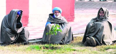 People sit on the ground to enjoy the sunshine at Amritsar on Tuesday. 