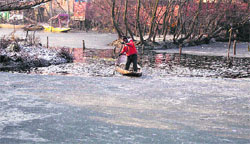 A man rows his boat as parts of the Dal Lake remained frozen on Tuesday in Srinagar.  Reuters