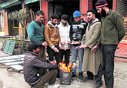 Shopkeepers warm themselves around a fire in front of their shops during a cold winter morning in Srinagar on Tuesday
