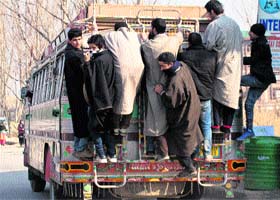 Dangerous drive: Youths travel on an overloaded bus in Srinagar on Wednesday