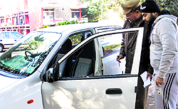 A PU security personnel inspects a damaged car in the parking lot of the Hostel No. 4 at Panjab University in Chandigarh on Thursday