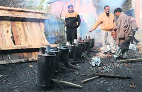 Government employees prepare stoves as part of the heating arrangement for offices in Kashmir on Thursday