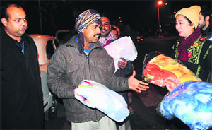 Ninette Vas Sharma, wife of Adviser to Administrator KK Sharma, distributes blankets among the poor in Chandigarh on Friday.