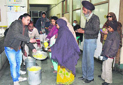 Members of Free Milk Sewa Society distribute food, milk and rusks to attendants of patients at Lord Mahavir Civil Hospital in Ludhiana. A Tribune Photo